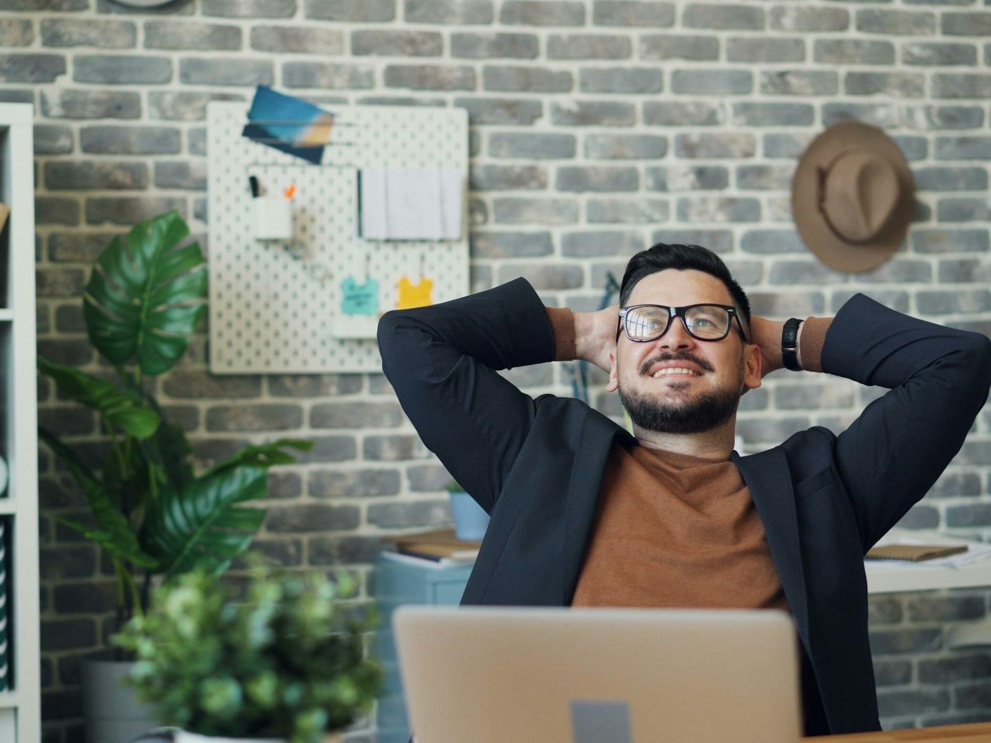 a man sitting at a desk with his hands behind his head