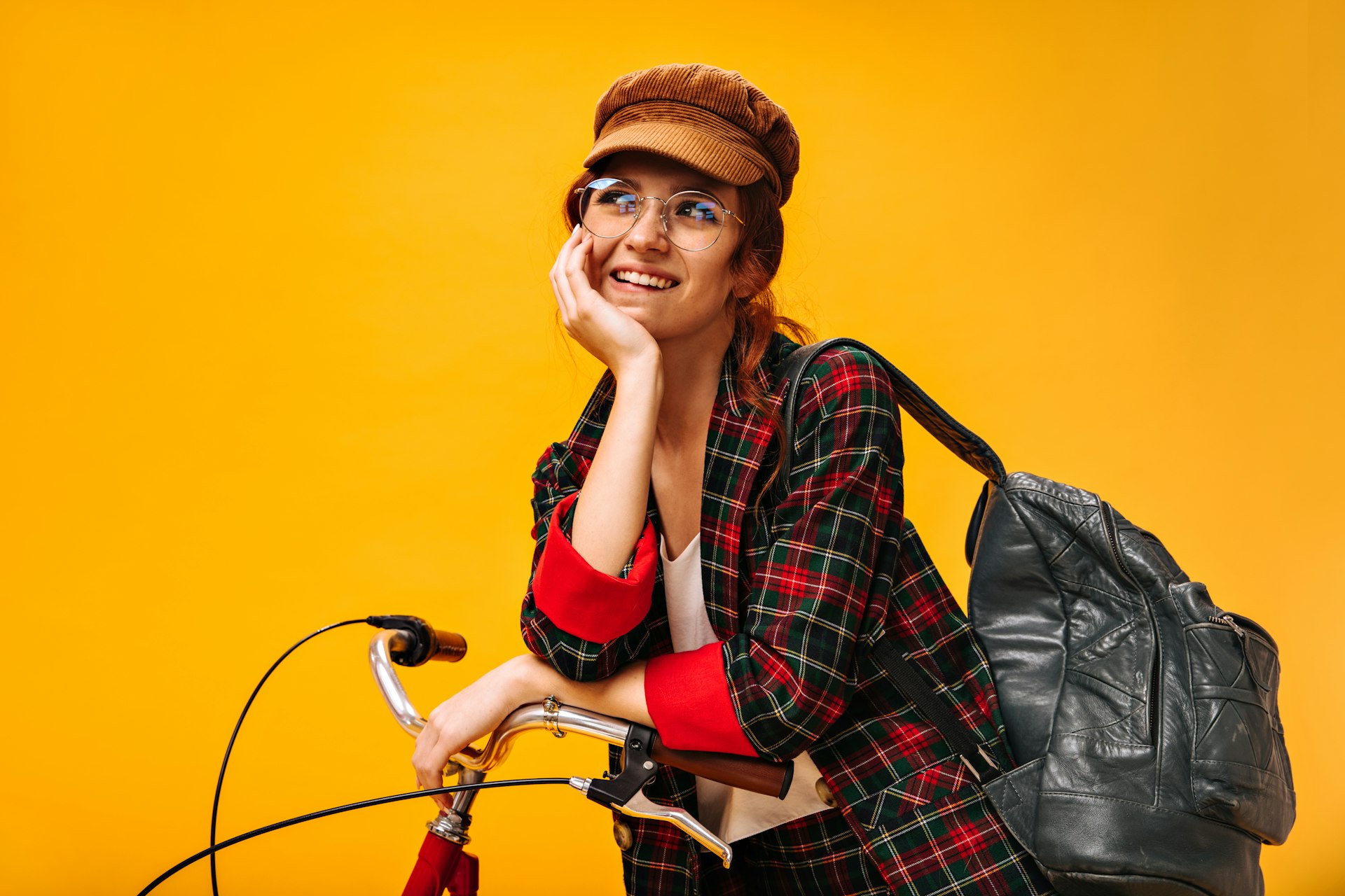 a woman sitting on top of a bike next to a black bag